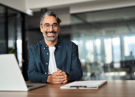 Giovane professionista uomo sorride, ha pc e block notes sulla scrivania