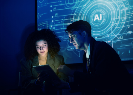 Due programmatori, una donna e un uomo, lavorano fianco a fianco con sfondo scritta AI.