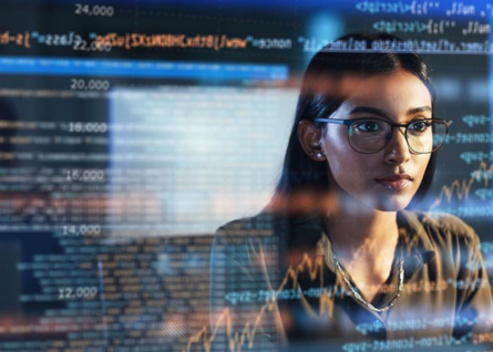 Giovane donna programmatrice guarda lo schermo con dati e codice 