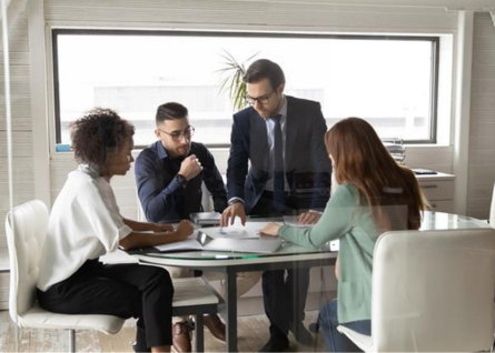 Gruppo di lavoro misto con uomini e donne che collaborano attorno a una grande scrivania