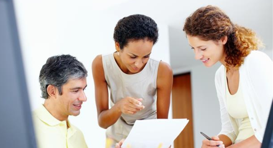 Un uomo e due donne leggono insieme un documento