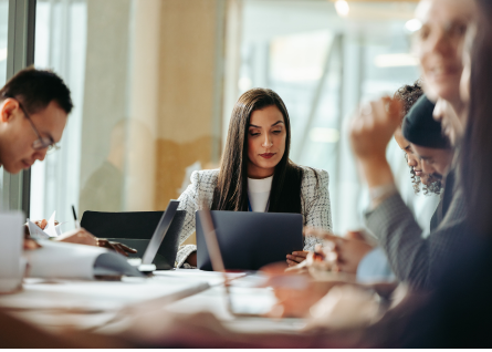 Una giovane professionista è concentrata al pc, intorno alcuni colleghi