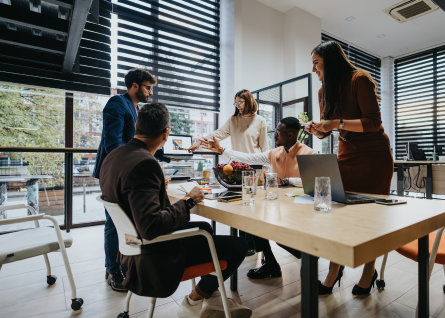 Giovani professionisti collaborano in sala riunioni, indicando lo schermo con le slide