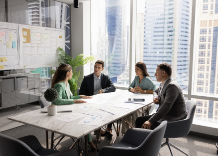 Quattro executive, due uomini e due donne, discutono intorno a una grande scrivania