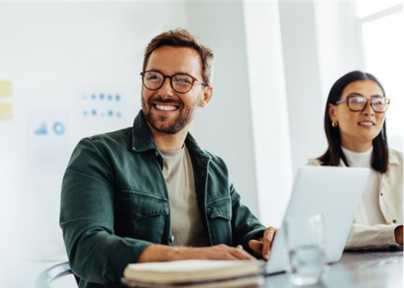 Un uomo e una donna lavorano uno accanto all'altro, davanti hanno un pc