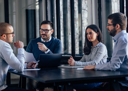Gruppo di quattro professionisti discute intorno a una scrivania